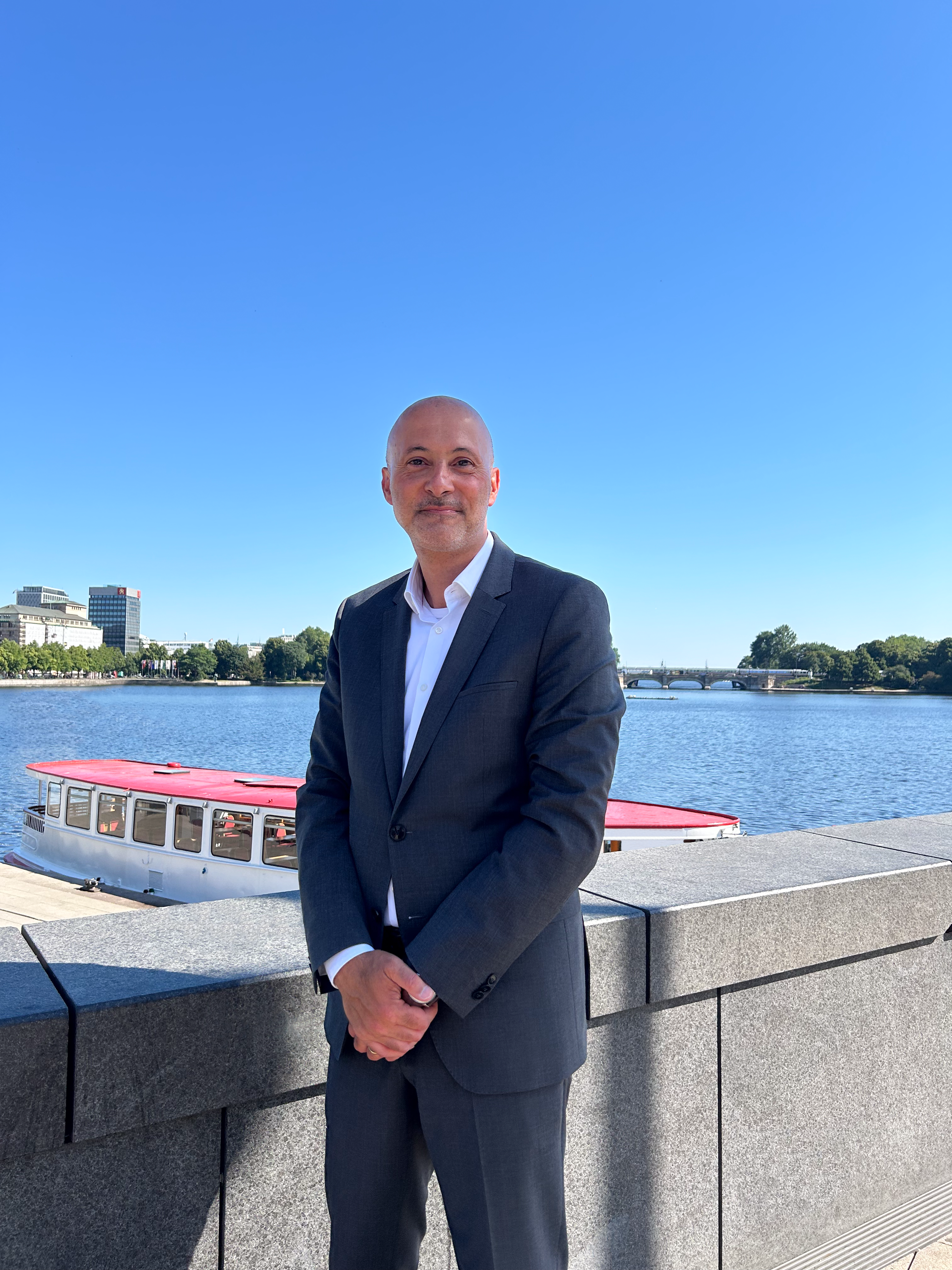 Geschäftsführer mit verkreuzten Armen, vor der Hamburger Alster. 
