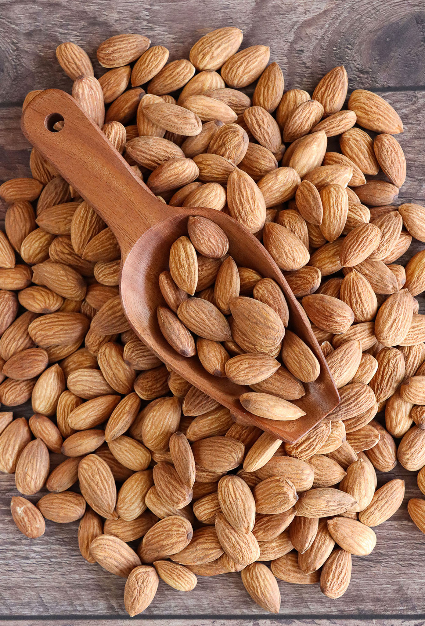Bitter apricot kernels and wooden spoon filled with kernels.